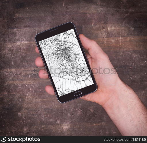 Hand holding a mobile phone with a broken screen, white display