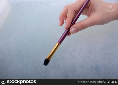 Hand holding a paint brush on water covered with foam