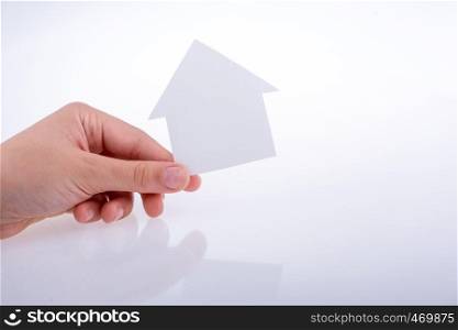 Hand holding a paper house on a white background