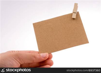 hand holding a paper placed in a clothespin on a white background
