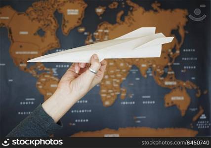Hand holding a paper plane against a map of the world