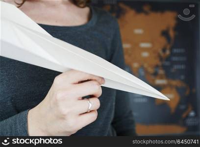 Hand holding a paper plane against a map of the world
