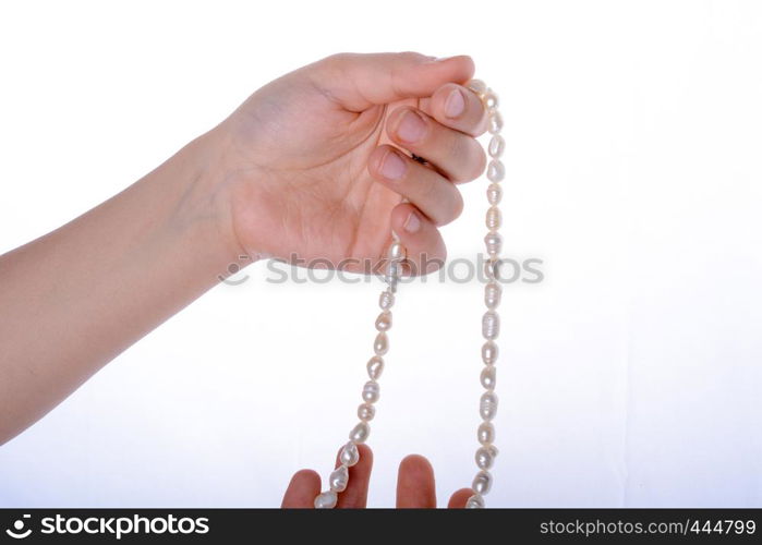 Hand holding a pearl necklace on a white background