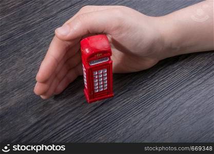 Hand holding a phone booth on a brown background