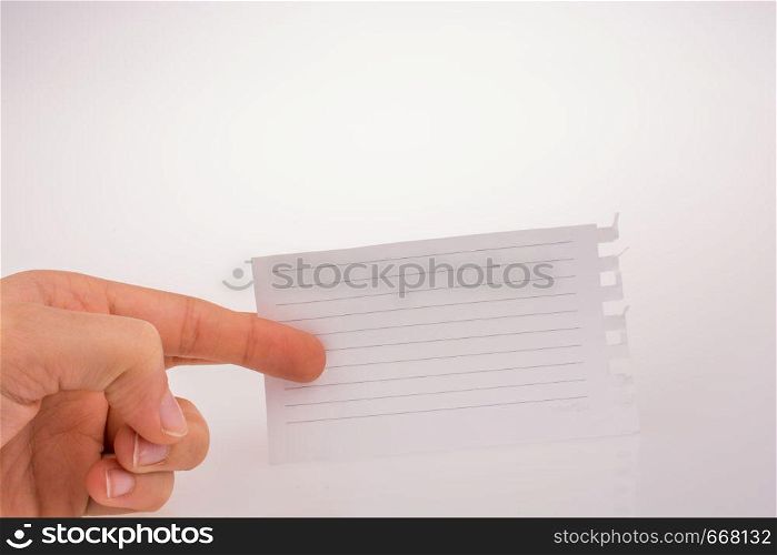 Hand holding a piece of lined paper on a white background