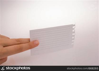 Hand holding a piece of lined paper on a white background