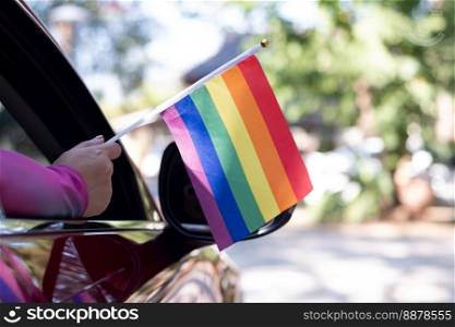 Hand holding a pride flag out the car window.