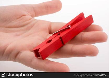 Hand holding a red clothespin on a white background