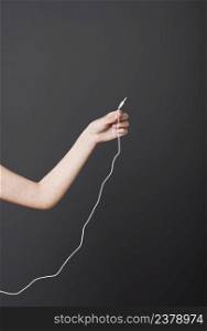 Hand holding a stereo audio cable over a gray background