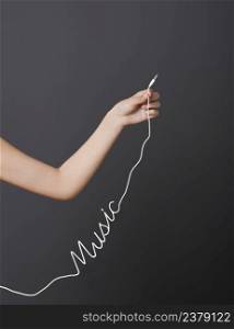 Hand holding a stereo audio cable with a shape of the word music