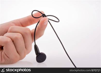 Hand holding a tied earphone on a white background