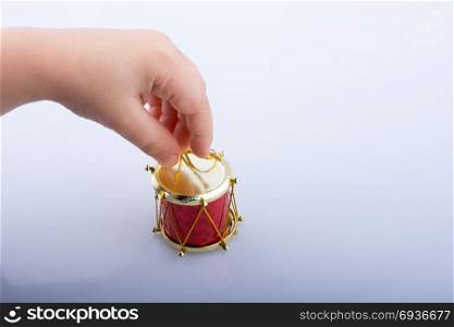 Hand holding a toy drum on a white background