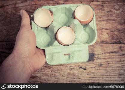 Hand holding a tray of egg shells at a table