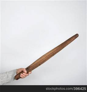 hand holding a very old wooden rolling pin on a gray background