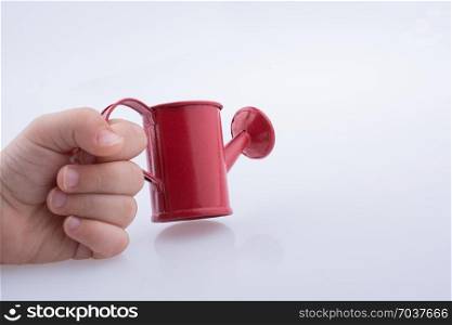 Hand holding a watering can without water on a white background