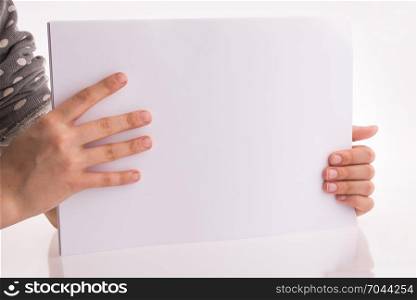 Hand holding a white blank sheet of paper on a white background