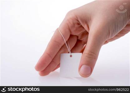 Hand holding a white tag with string