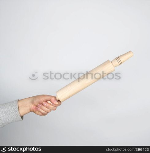 hand holding a wooden rolling pin on a gray background