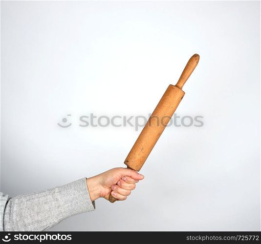hand holding a wooden rolling pin on a gray background, copy space