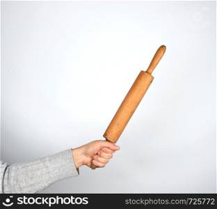 hand holding a wooden rolling pin on a gray background, copy space