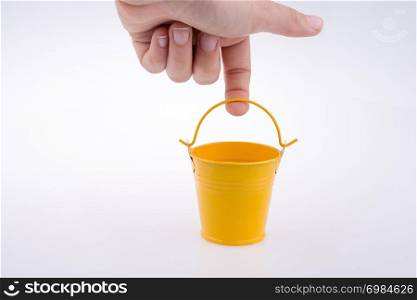Hand holding a yellow bucket on a white background