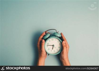 Hand holding an alarm clock on blue background for the concept of time management.