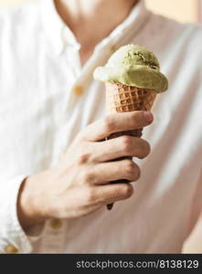 Hand holding an ice cream cone of green tea. . ice cream cone of green tea. 