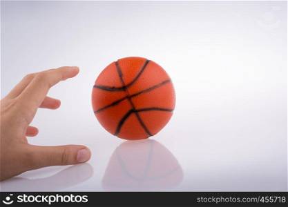 Hand holding an orange basketball model on a white background