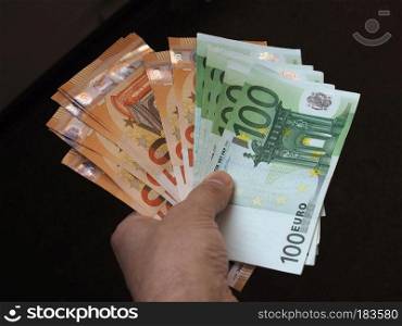Hand holding and giving Euro banknotes money (EUR), currency of European Union. Hand with Euro notes, European Union