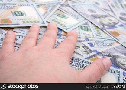 Hand holding banknotes on other banknotes of US dollar spread around