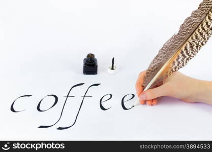 Hand holding bird feather writing the word coffee with black ink on white paper