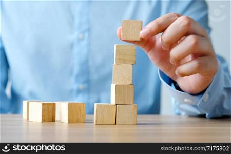 Hand holding blank wooden cubes on wooden table, business concept background, mock up, template