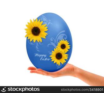Hand holding Blue Easter egg with yellow flowers on white background.