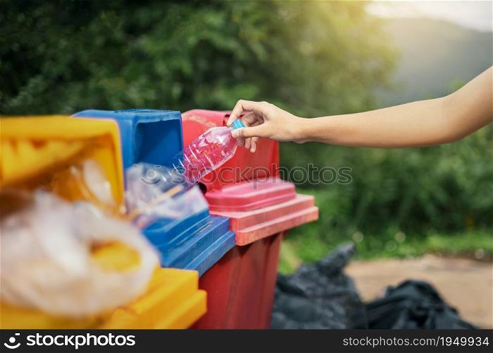 hand holding bottle plastic garbage into trash in park