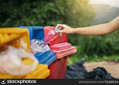 hand holding bottle plastic garbage into trash in park