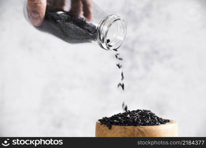 hand holding bottle with black rice near bowl