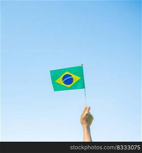 hand holding Brazil flag on blue sky background. September Independence day and Happy celebration concepts