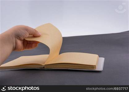 Hand holding brown color notebook on a white background