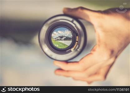 Hand holding camera lens with old city of Salzburg in it, close up