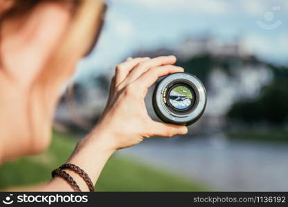 Hand holding camera lens with old city of Salzburg in it, close up