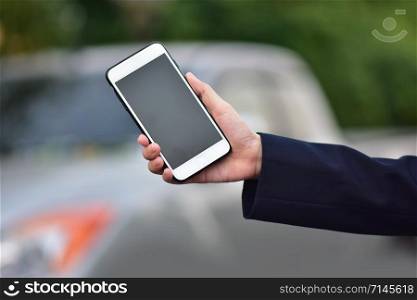 Hand holding Cellphone or Mobile smart phone car parked background,Telephone mobile