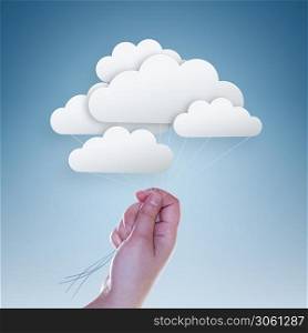 hand holding clouds on light blue background