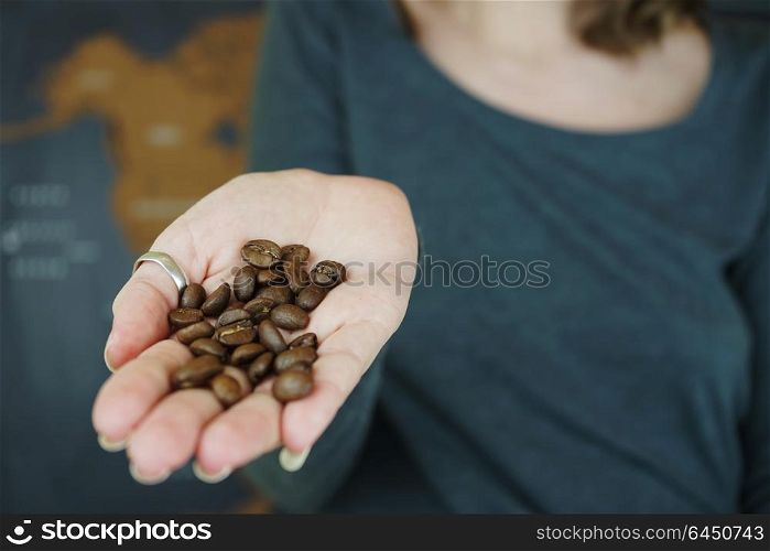 Hand holding coffee beans against a map of the world