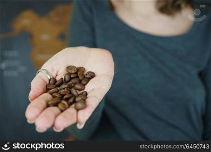 Hand holding coffee beans against a map of the world