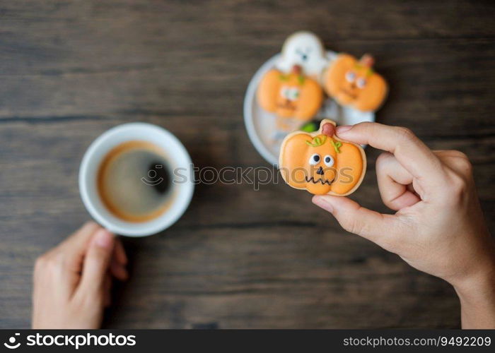 hand holding coffee cup during eating funny Halloween Cookies. Happy Halloween day, Trick or Threat, Hello October, fall autumn, Traditional, party and holiday concept