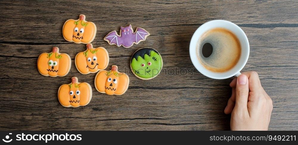 hand holding coffee cup during eating funny Halloween Cookies. Happy Halloween day, Trick or Threat, Hello October, fall autumn, Traditional, party and holiday concept