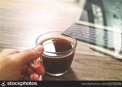 Hand holding Coffee cup or tea and Digital table dock smart keyboard,stylus pen on wooden table,filter effect