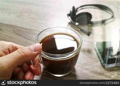 Hand holding Coffee cup or tea and voip headset,smart phone on wooden table,filter effect,icon screen