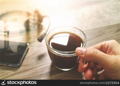 Hand holding Coffee cup or tea and voip headset,smart phone on wooden table,filter effect