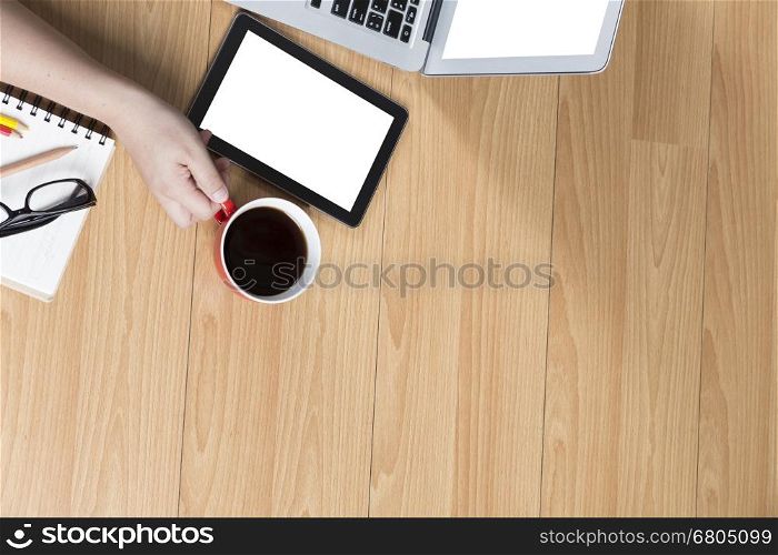 hand holding coffee cup with tablet and computer notebook on office desk